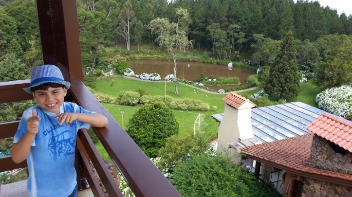 Criança rindo com área verde e lago